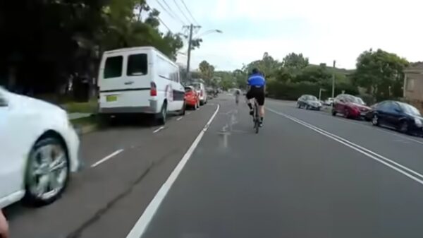 Wielrenner die fietspad niet wil gebruiken met pijnlijk kennis met aanhangwagen